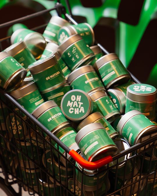Close-up of OHMATCHA tins in a cart